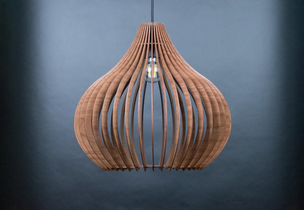 May include: A pendant light fixture constructed from multiple curved, vertical wooden slats arranged in a teardrop shape. The structure features a natural brown wood grain finish and is suspended by a single black cord with a visible light bulb inside.